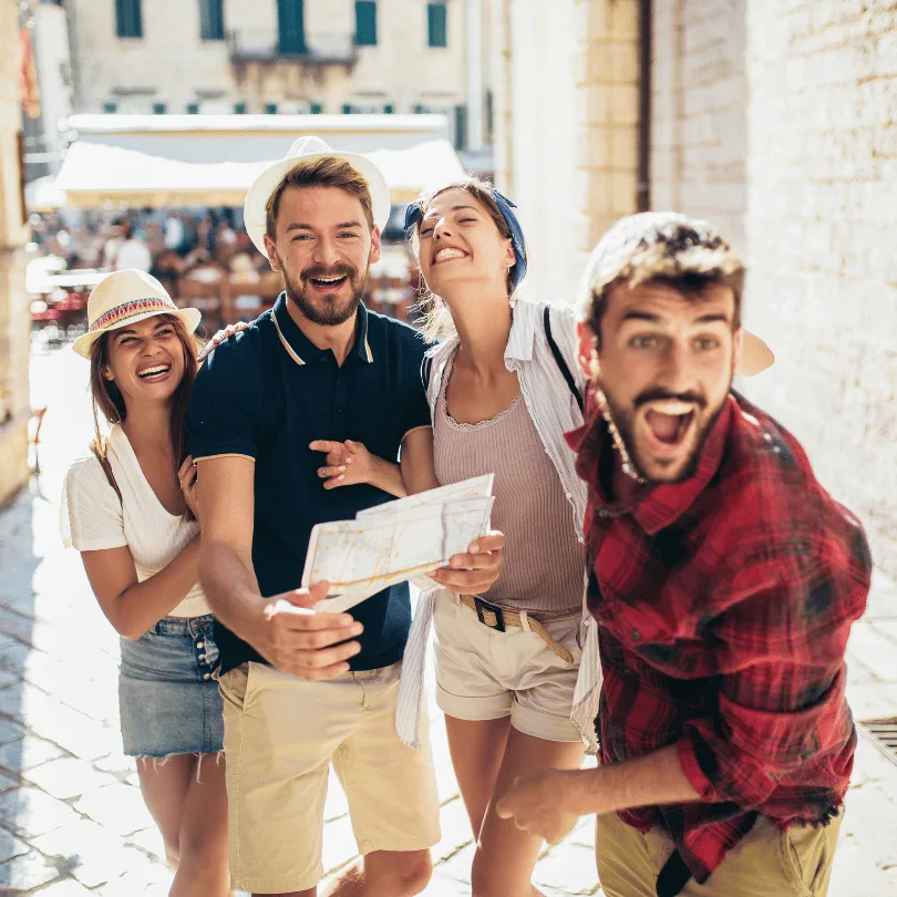 Businessplan Reiseveranstalter von Dirk Leimkuhl 3 Gruppe von vier Touristen mit Hut und Landkarte in einer südländischen Stadt, fröhlich lächelnd