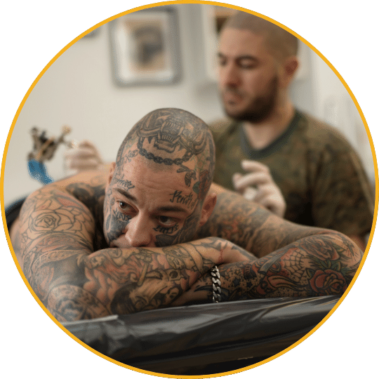 Tätowierter männlicher Kunde mit umfangreichen Tattoos im Tattoostudio