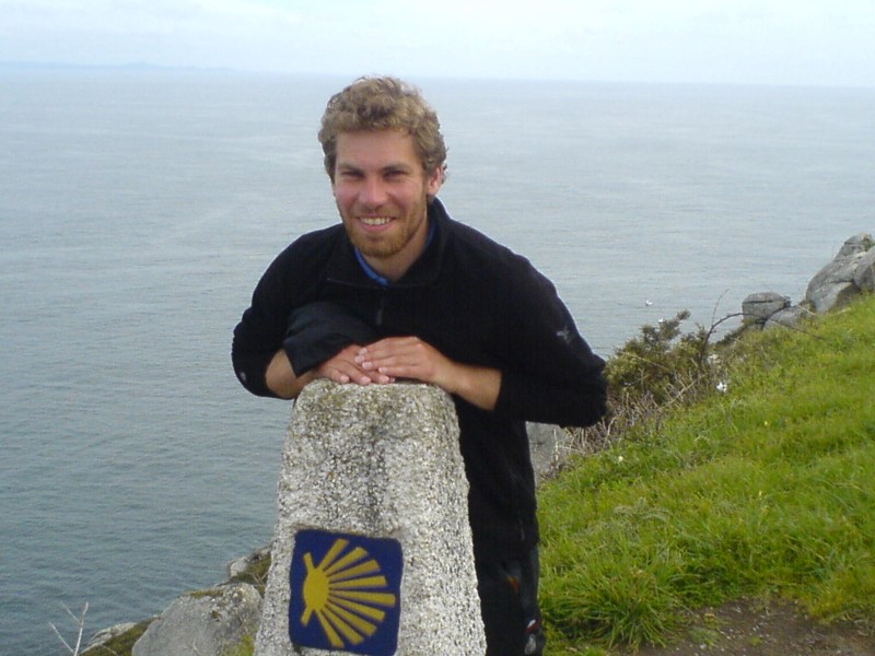 Christoph Erkens am Kap Finisterre mit Muschel-Logo, Meereshintergrund