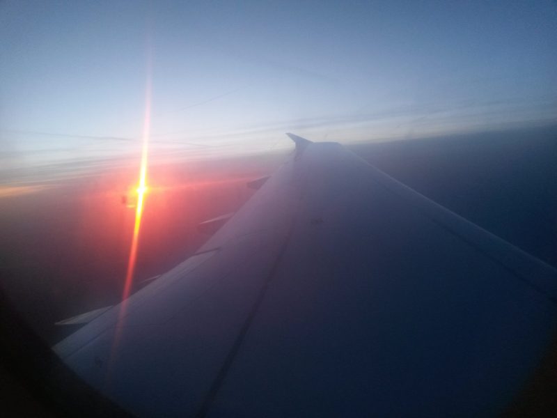 Flugzeugfenster mit Sonnenaufgang und Tragfläche