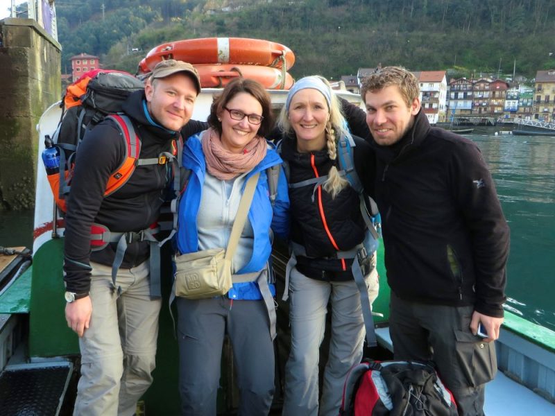 Vier Pilger in Wanderausrüstung posieren auf Boot mit Rettungsring