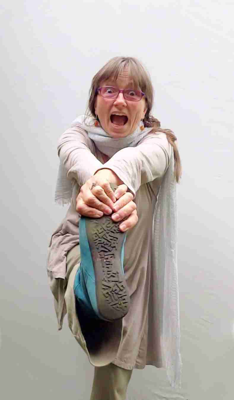 Mahashakti Uta Engeln in freudiger Pose, Baum-Asana andeutend, mit rosa Brille und Schal