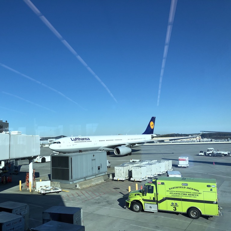 Lufthansa-Flugzeug am Gate mit Bodenfahrzeugen und blauem Himmel