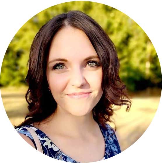 Profilbild einer Frau mit braunen welligen Haaren vor grünem Naturhintergrund, kreisförmiger Zuschnitt