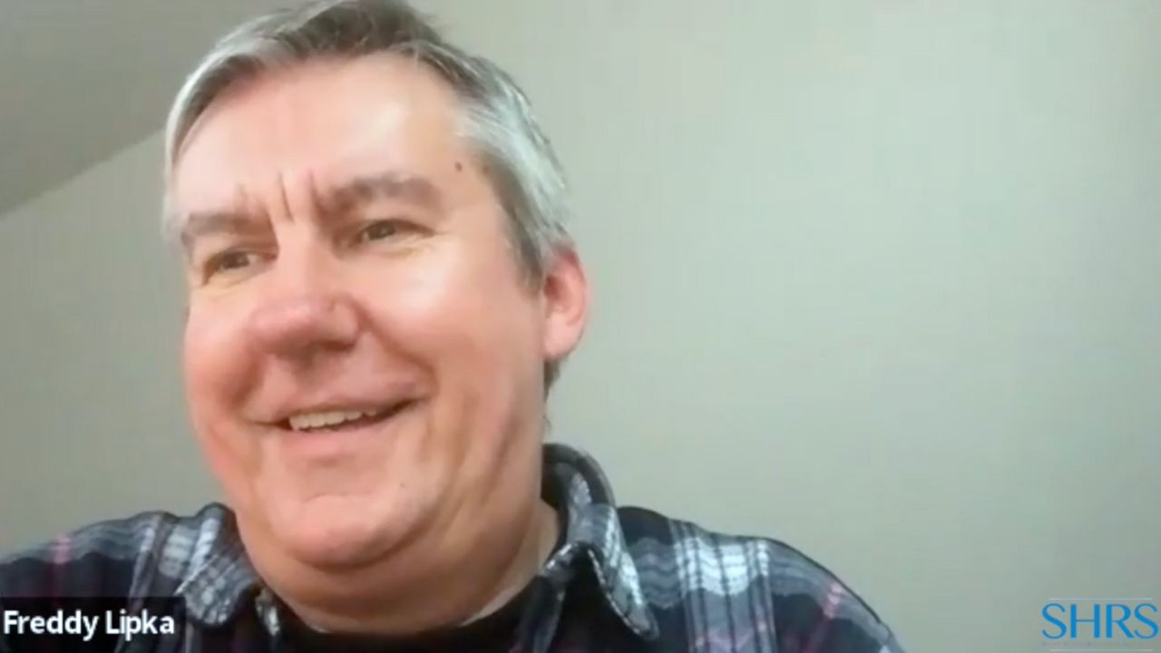 Älterer Mann mit grauem Haar, karriertem Hemd, Name Freddy Lipka eingeblendet