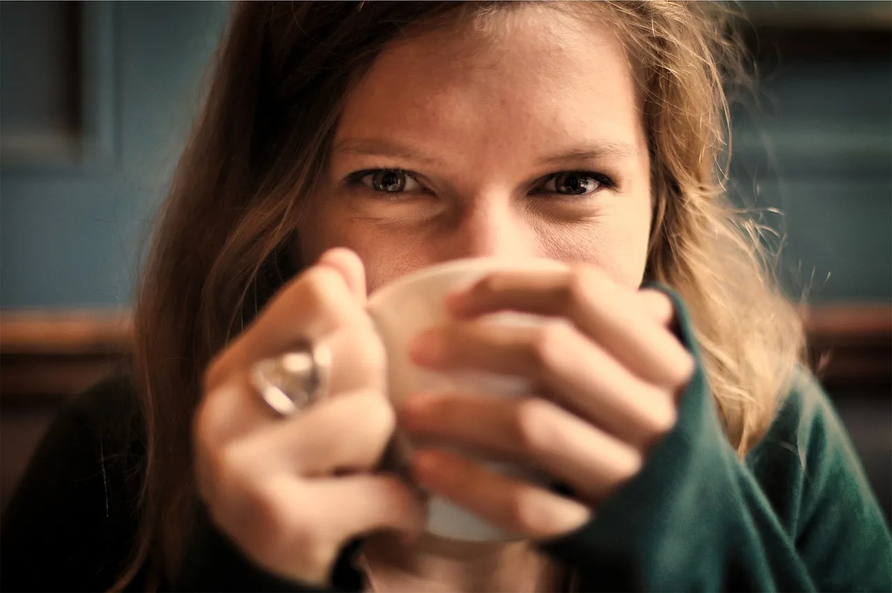 Das Glückliche Gehirn – Positive Neuroplastizität Training 3 Frau mit braunem Haar hält Teetasse – Porträt von vorne mit konzentriertem Gesichtsausdruck