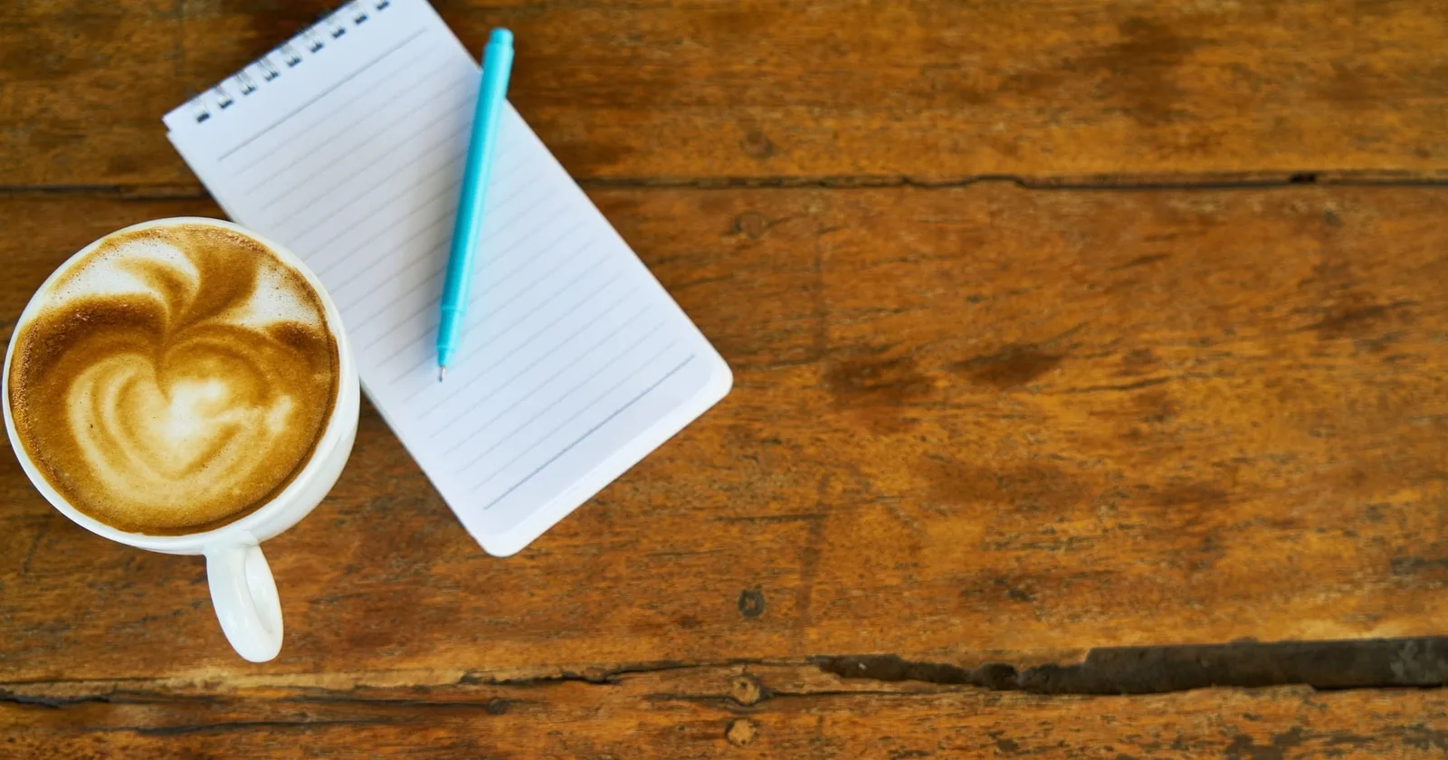 Das Leben ohne Dich – Trauer-Workbook 3 Ansicht von oben auf Schreibtisch mit Kaffee mit Herz-Latte Art und Notizbuch mit Stift auf Holz