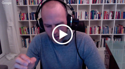 Mann mit Kopfhörer sitzt vor Bücherregal während Webinar-Aufnahme