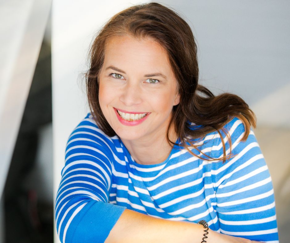 Simone Stalberg in blauem Streifenshirt, lächelt freundlich in Kamera gegen neutralem Hintergrund