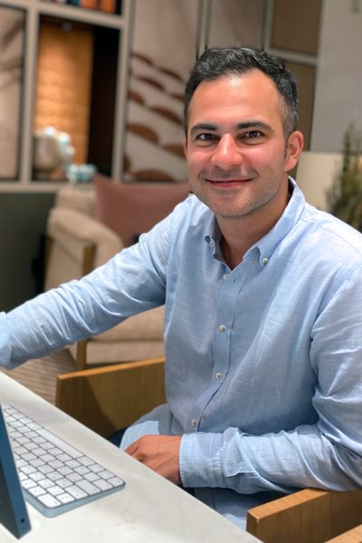 Portrait Hamed Farhadian, Mann in blauem Hemd sitzend am Schreibtisch mit Keyboard, Büroumgebung