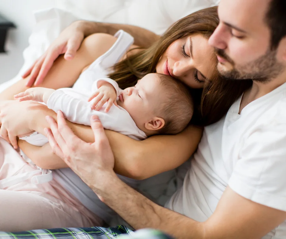 Junge Familie mit Neugeborenem im Bett, Eltern mit Baby in entspanntem Moment