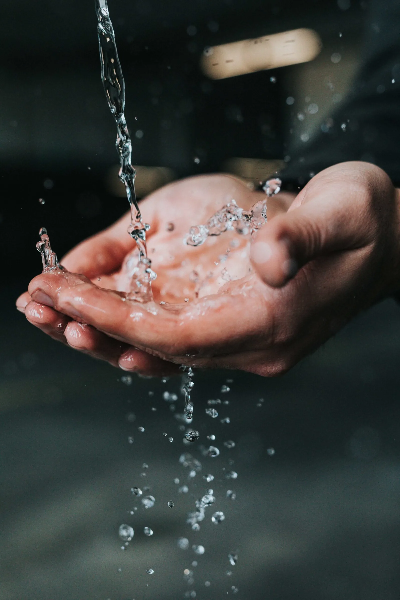Wasser fließt über offene Hände, Reinigung und Loslassen symbolisierend
