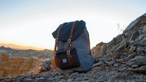 Dunkelblauer Wanderrucksack steht auf steinigem Berg bei Sonnenaufgang