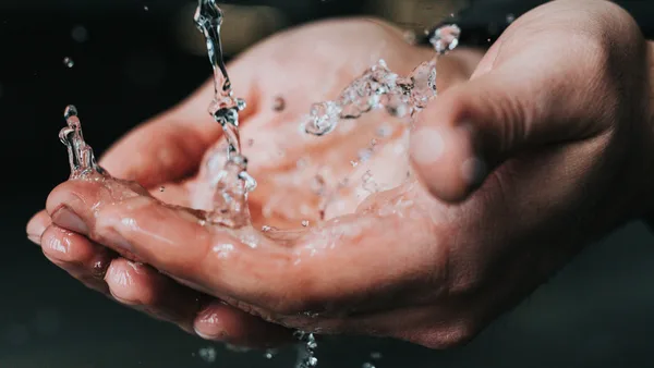 Wasser fließt über offene Hände, symbolisiert emotionale Reinigung und Hygiene