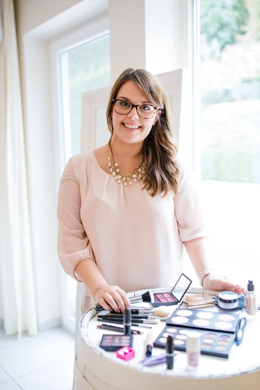 Der Meerjungfrauenzopf – das Videotraining von Laurie Ibsen 10 Junge Frau mit Brille vor Make-up-Produkten und Pinseln