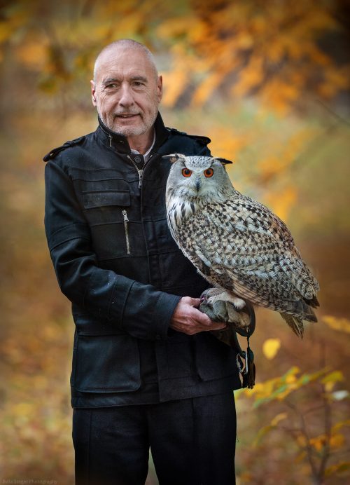 Karl Gamper hält Eule in den Händen vor herbstlichem Hintergrund