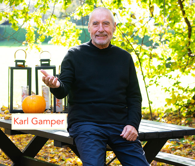 Karl Gamper sitzt auf Bank mit Kürbis und Laternen, Herbstsetting