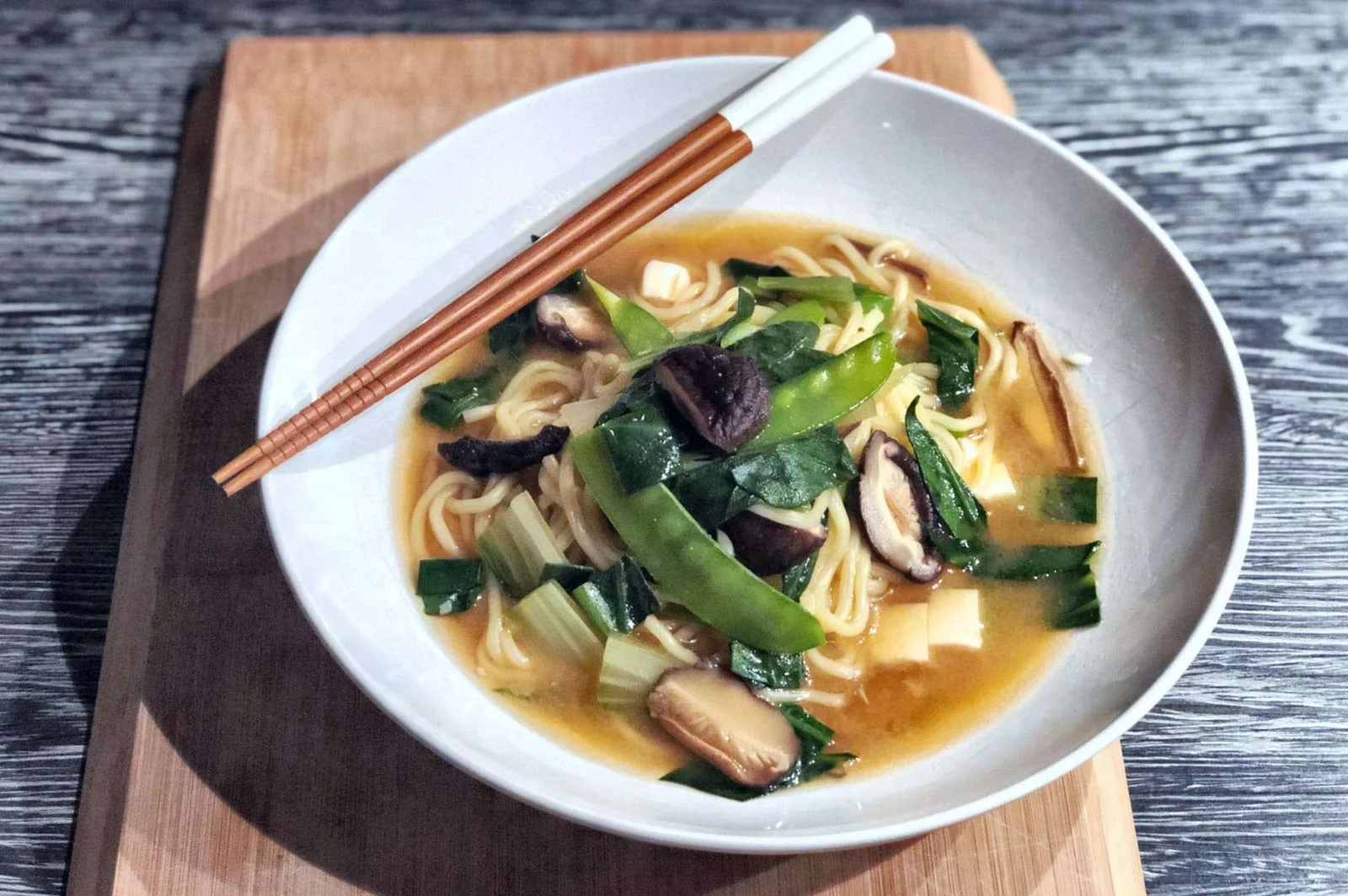 Ramen-Suppe mit Nudeln, Tofu, Pilzen und grüner Zwiebel auf weißem Teller