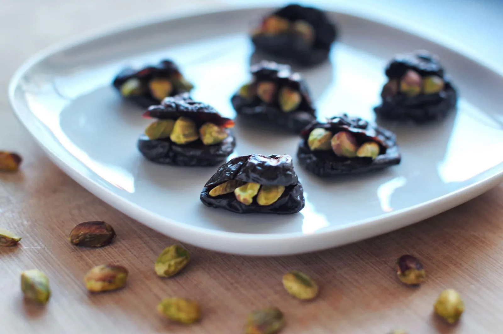 Schwarze Päckchen mit Pistazien-Füllung auf weißem Teller als vegane Appetizer