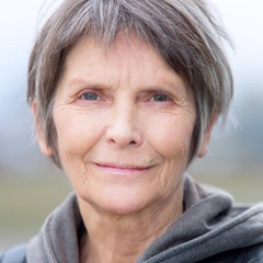Porträt einer älteren Frau mit grauem Haar vor unscharfem Hintergrund