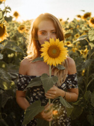 Frau hält Sonnenblume vor Sonnenblumenfeld, DGX II Preset, goldenes Licht