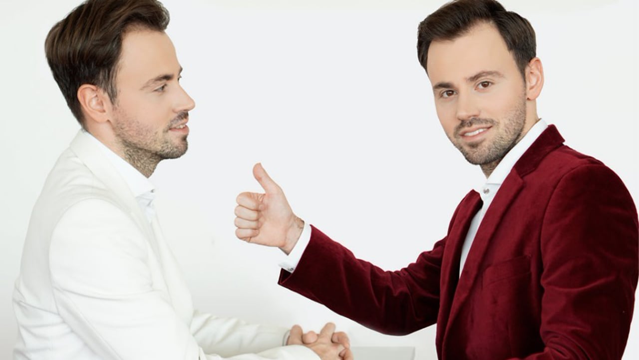 Zwei Männer in Geschäftskleidung im Gespräch mit Handschlag, einer im weißen Hemd, einer im bordeauxroten Blazer
