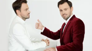 Zwei Männer in Geschäftskleidung im Gespräch, einer im weißen Hemd, einer im bordeauxroten Blazer, mit Handschlag