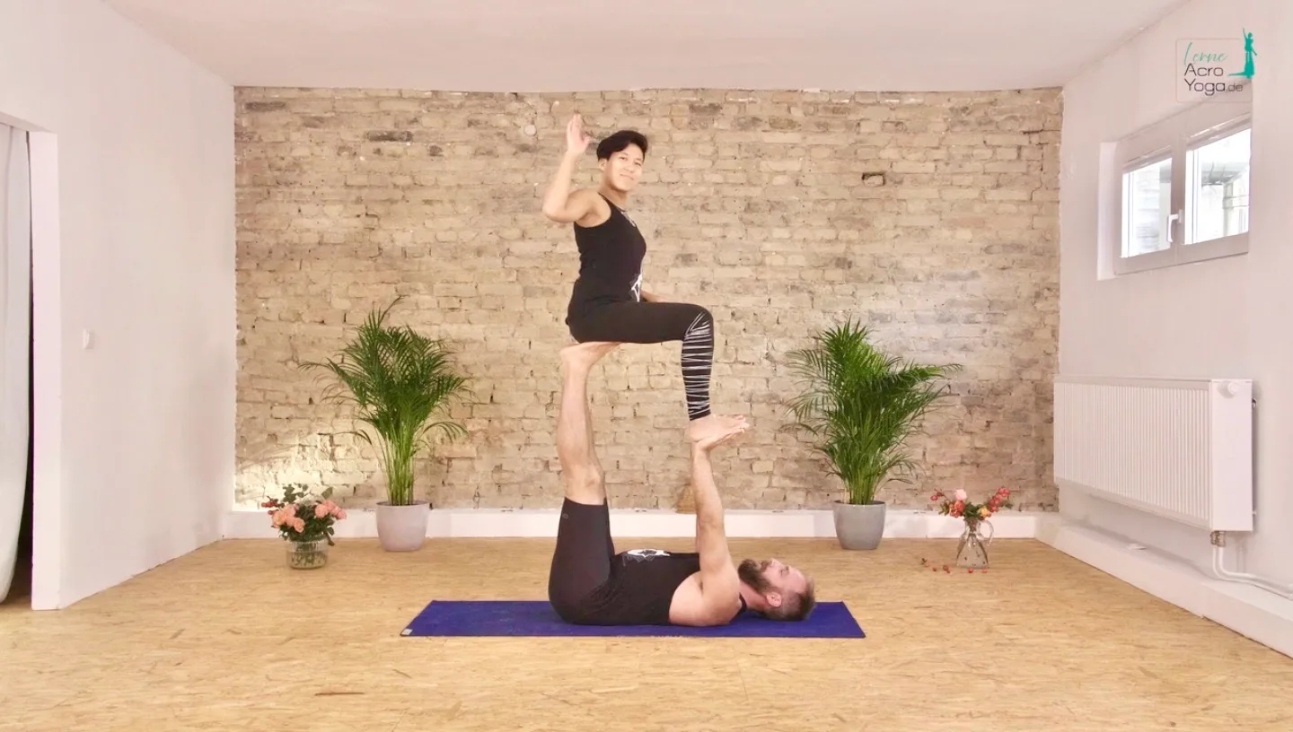 Die AcroYoga Uni – Mit Spiel & Spaß AcroYoga lernen 23 AcroYoga Partnerübung mit Partner in Fliegen-Position auf den Beinen des unten liegenden Partners im Yogastudio