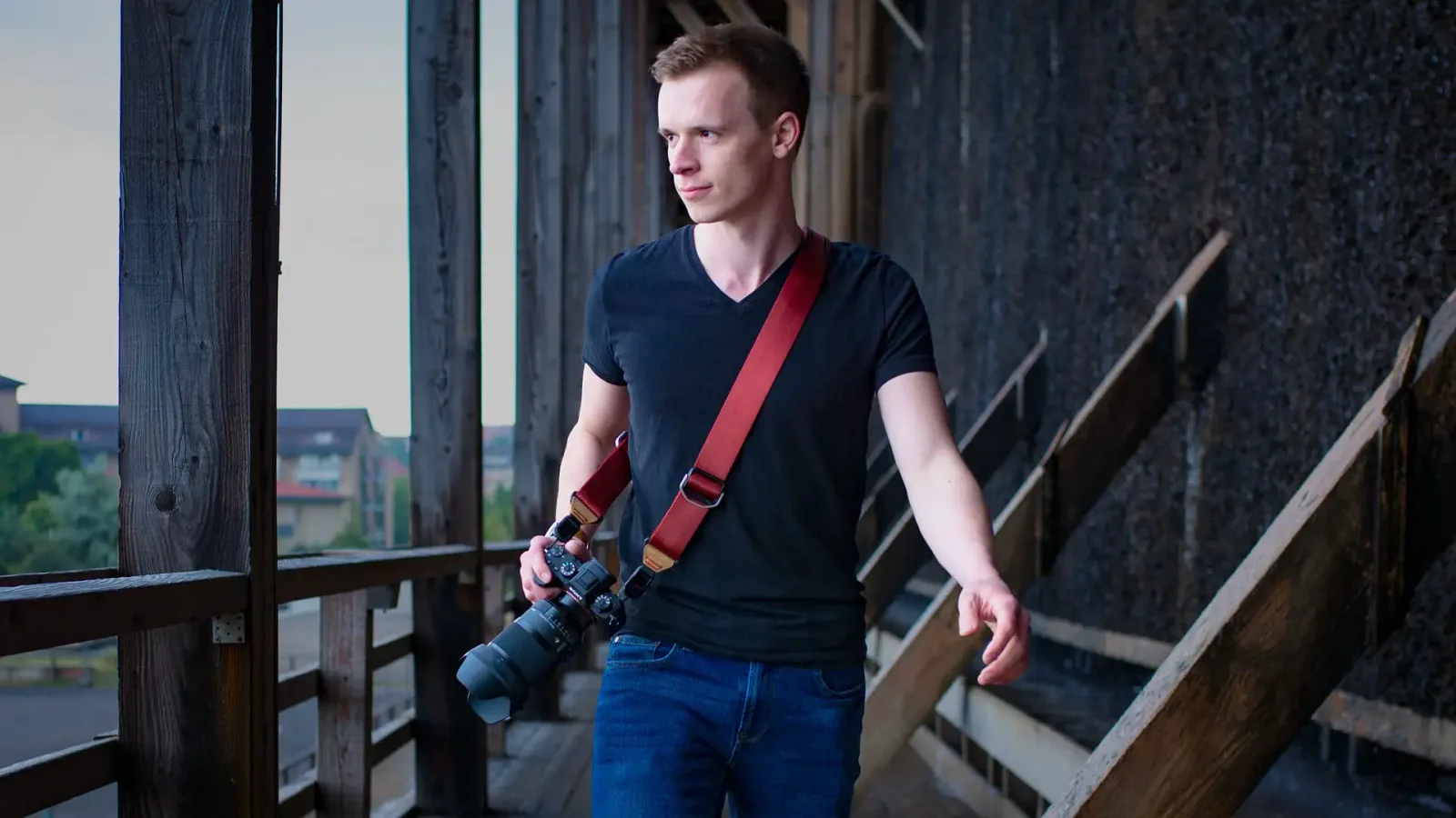 Fotograf mit Kamera auf Schulter an urbaner Industrielocation, Die Akademie