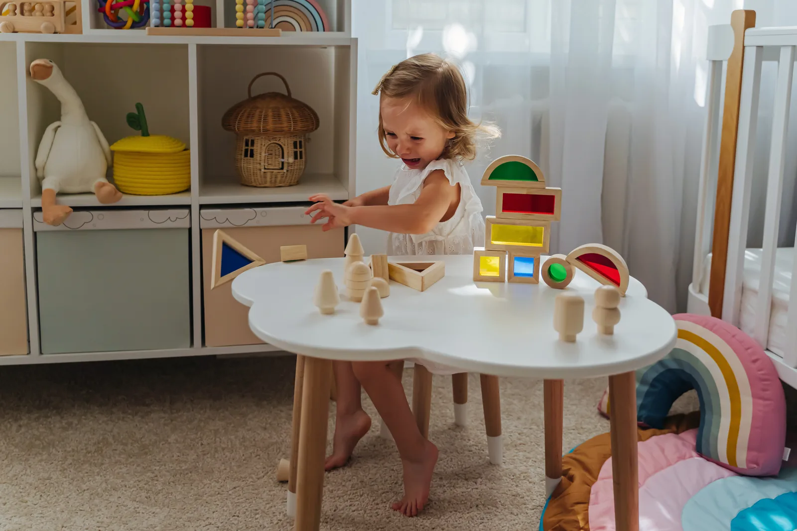 Kleines Kind spielt mit Holzspielzeug am Tisch in einer hellen Kita-Umgebung