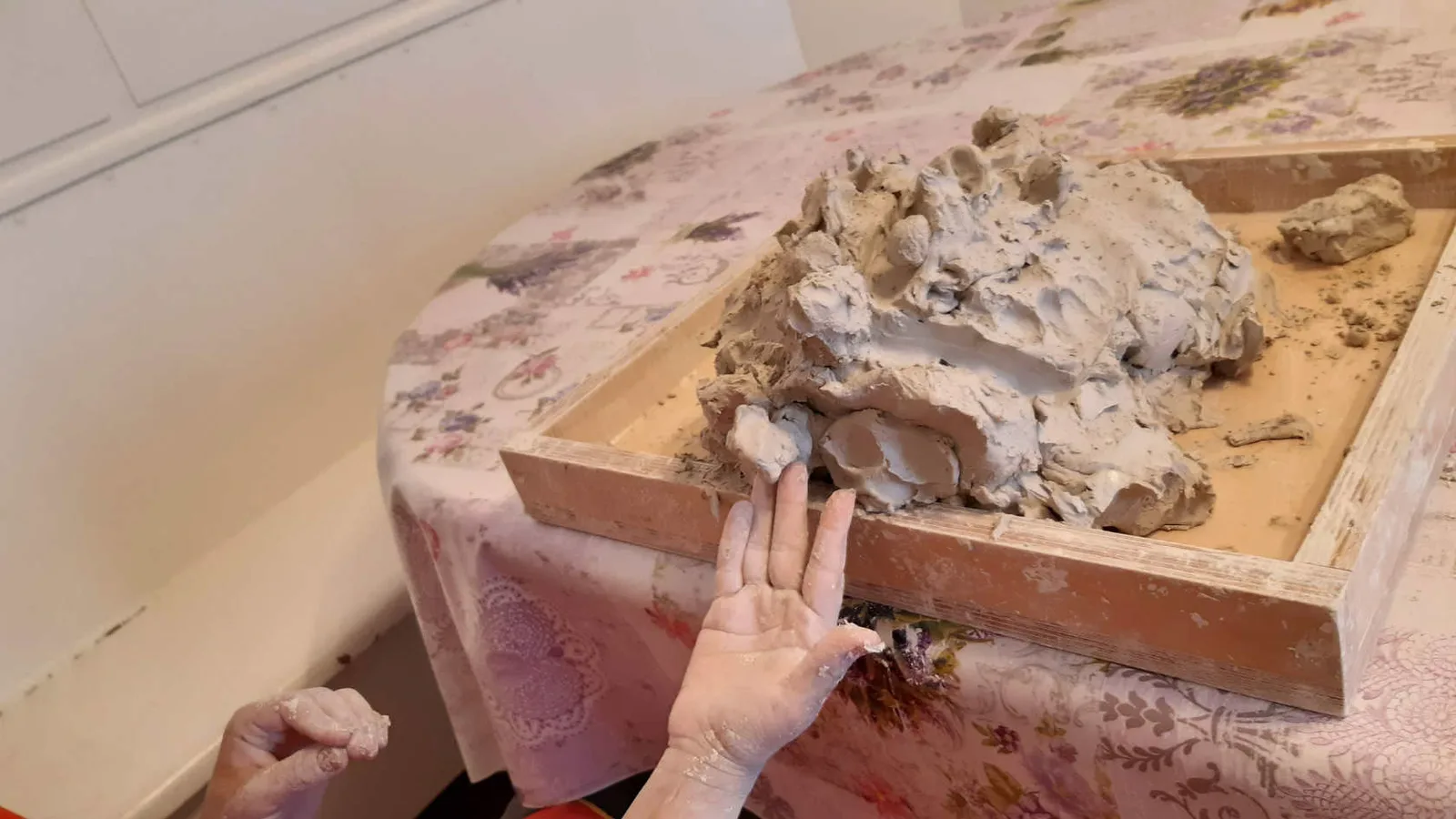Hand formt Tonmasse im Tonfeld, therapeutisches Gestalten mit Naturmaterial
