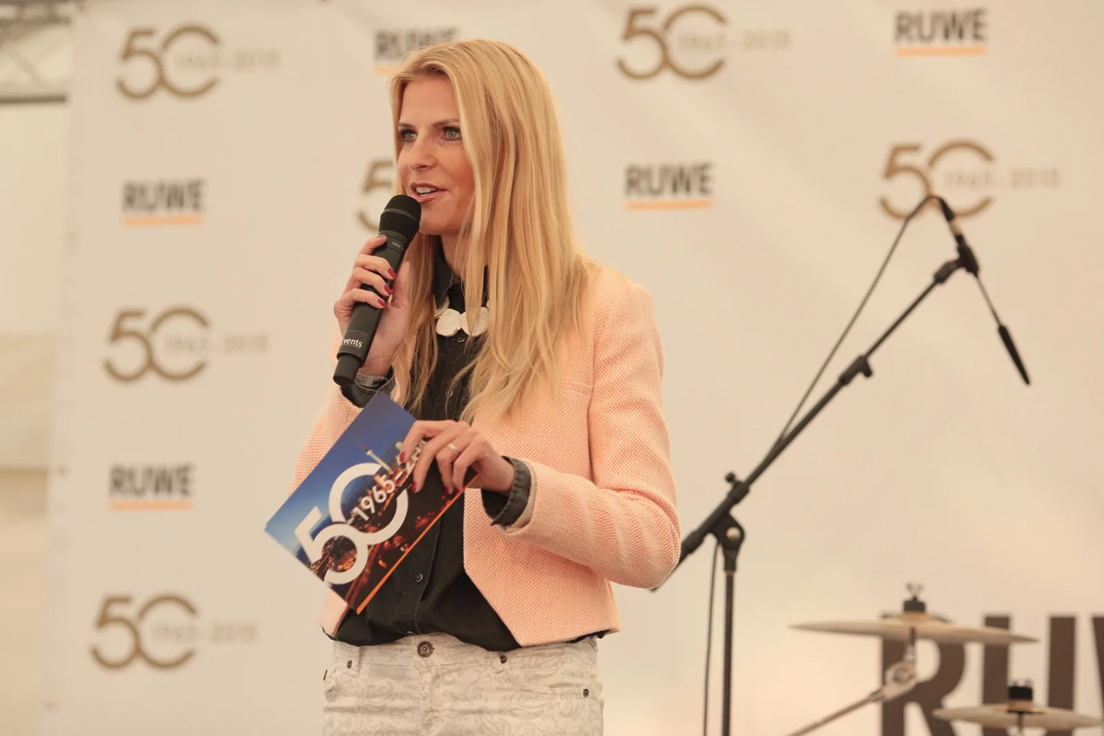 Tanja Bülter spricht auf der 50C Jahreskonferenz mit Mikrofon und Unterlagen