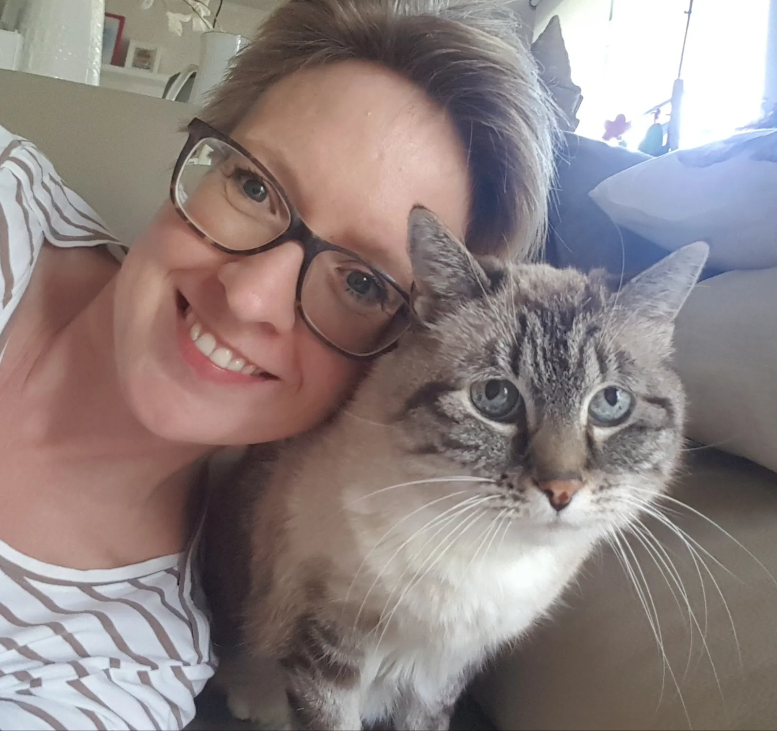 Sonja Tschöpe mit Brille lacht wange an wange mit graugetigerte Katze Mischu