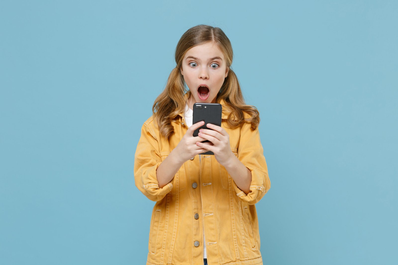Digital-Club – Medienkompetenz-Live-Kurs für Kinder von Ben Fisch 3 Blonde Mädchen in gelbem Jeansjacke auf blauem Hintergrund, schockiert mit Handy