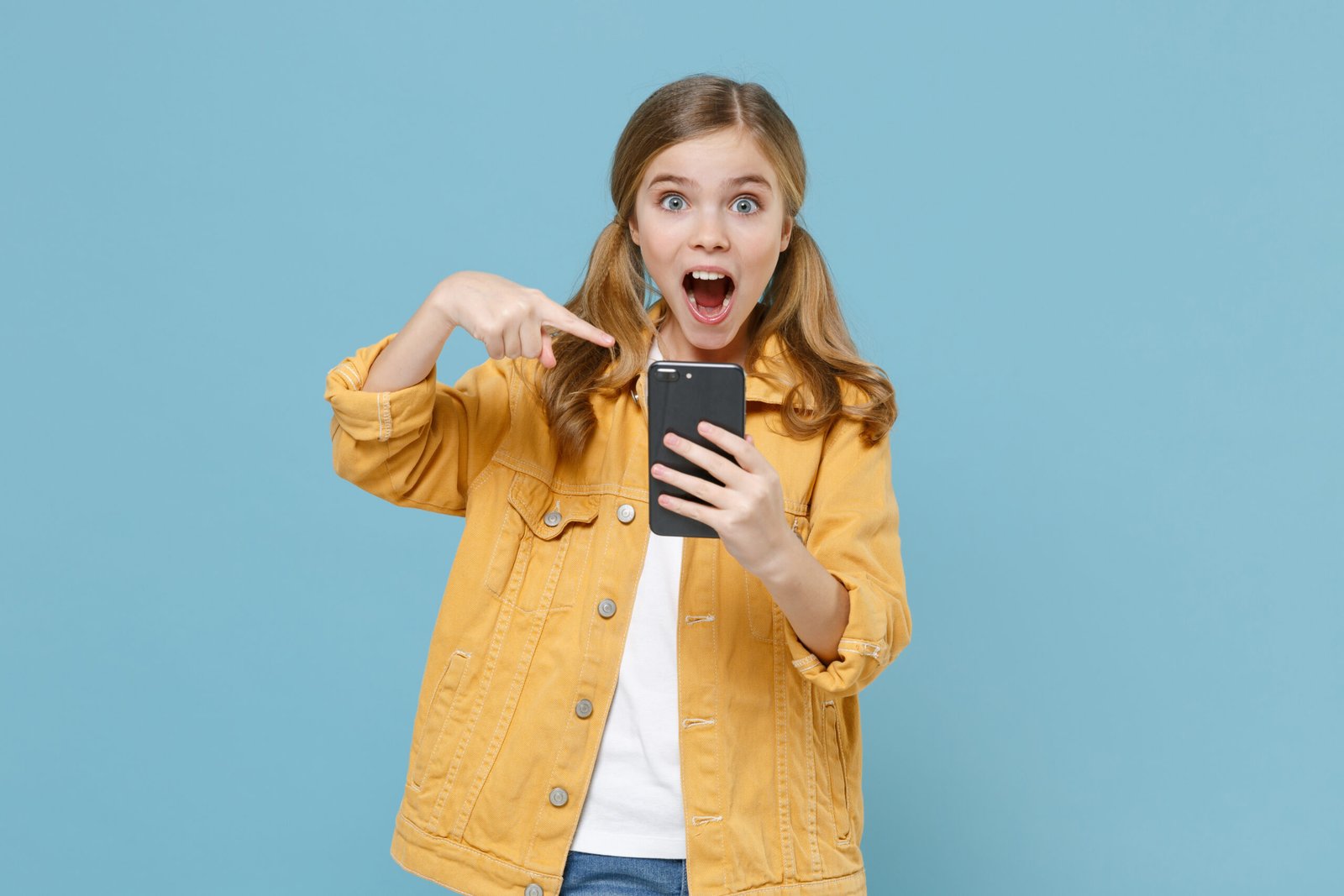 Digital-Club – Medienkompetenz-Live-Kurs für Kinder von Ben Fisch 21 Blonde Mädchen in gelbem Jeansjacke auf blauem Hintergrund, schockiert zeigend auf Handy