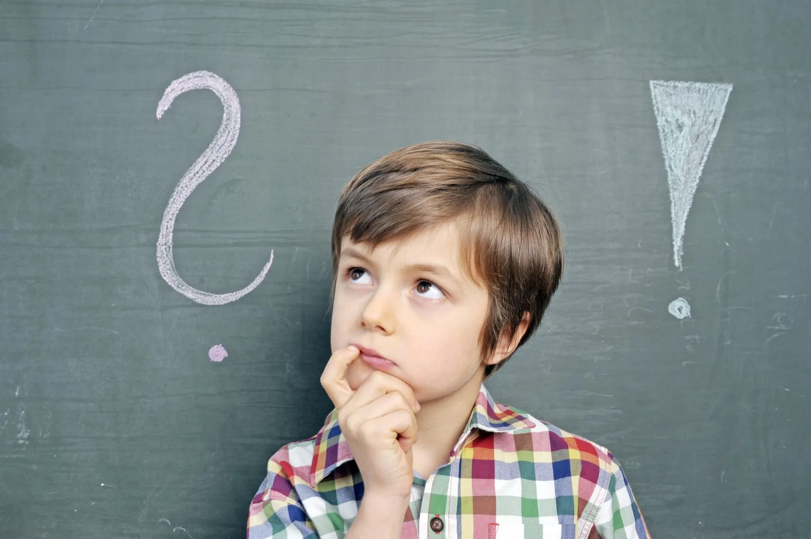 Digital-Club – Medienkompetenz-Live-Kurs für Kinder von Ben Fisch 5 Kind mit kariertem Hemd schaut nachdenklich, mit Fragezeichen und Ausrufezeichen an Schultafel