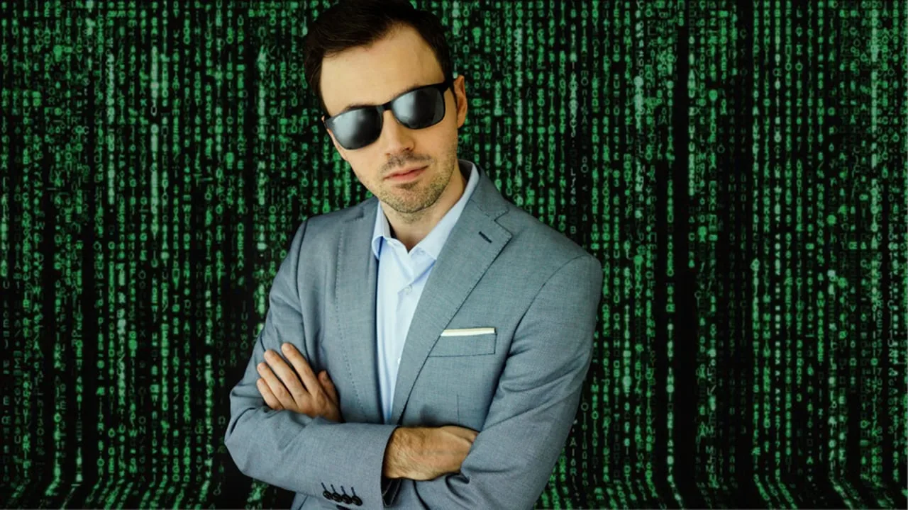 Mann im grauen Anzug mit Sonnenbrille vor grünem Matrix-Code-Hintergrund