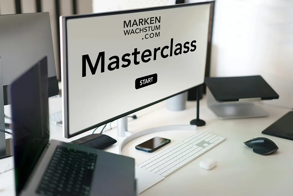 Monitor mit Bildschirmtext "Masterclass START" auf modernem Schreibtisch mit Tastatur und Zubehör