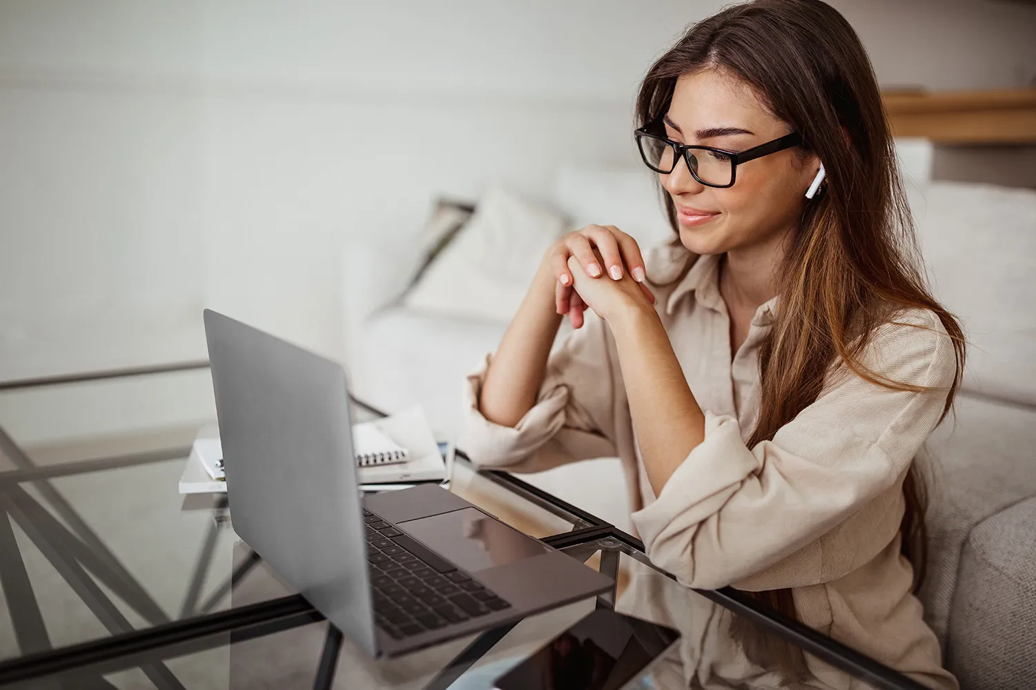 Frau mit Brille am Laptop, konzentriert arbeitend mit Notizbüchern auf dem Schreibtisch
