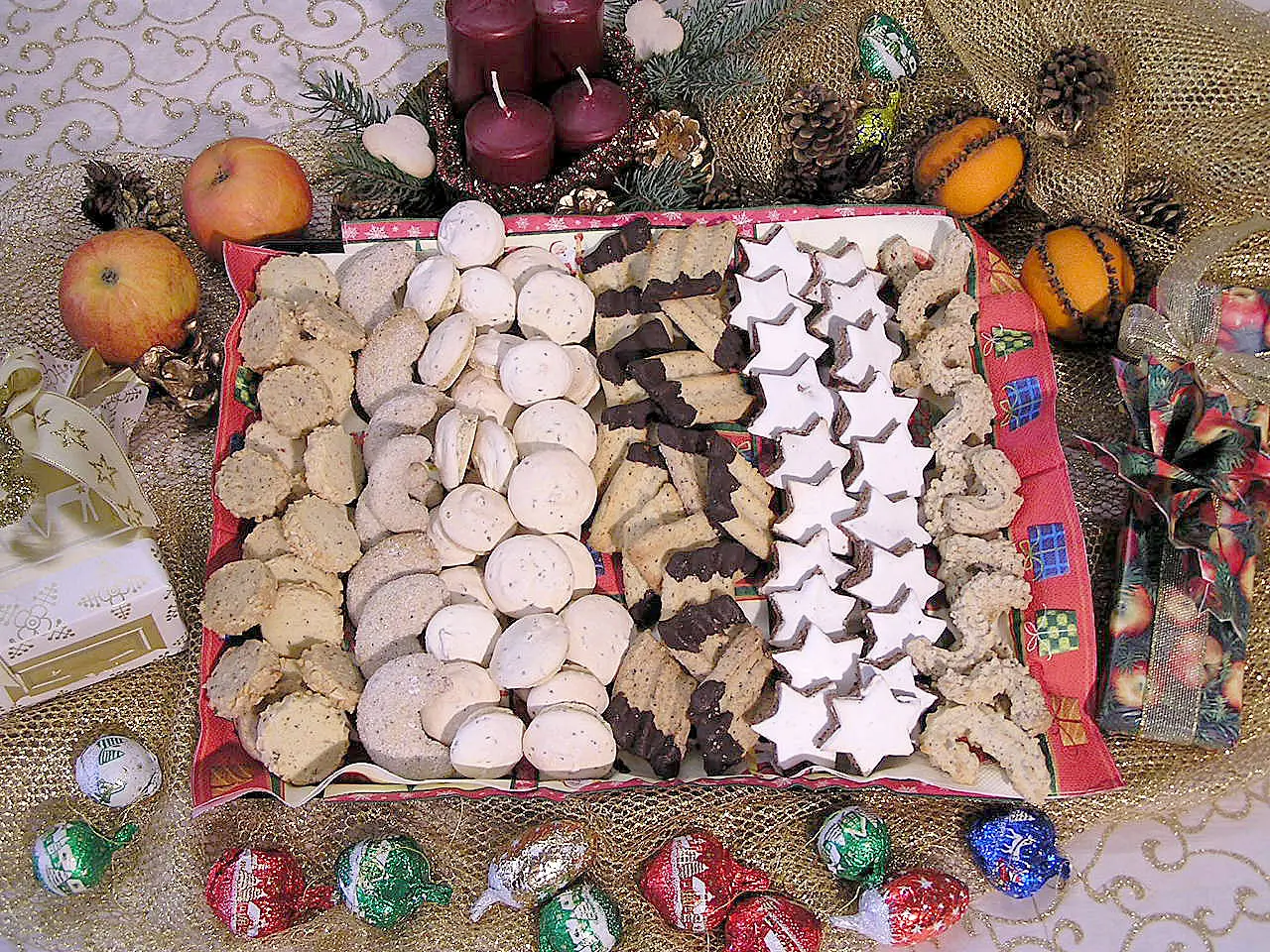 Rheinisches Nussgebäck, Anisgebäck und Spritzgebäck auf rotem Tablett mit Weihnachtsdekoration und Äpfeln