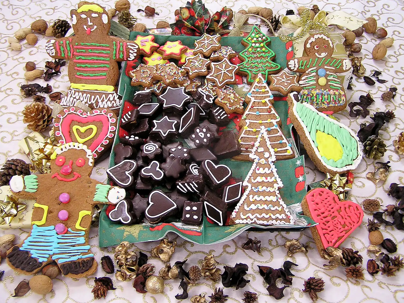Lebkuchen-Figuren und -Teile mit farbiger Zuckerguss-Dekoration auf grünem und beigem Untergrund