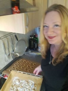 Frau in schwarzem Oberteil vor Backstudio mit Backblech voller Gebäck