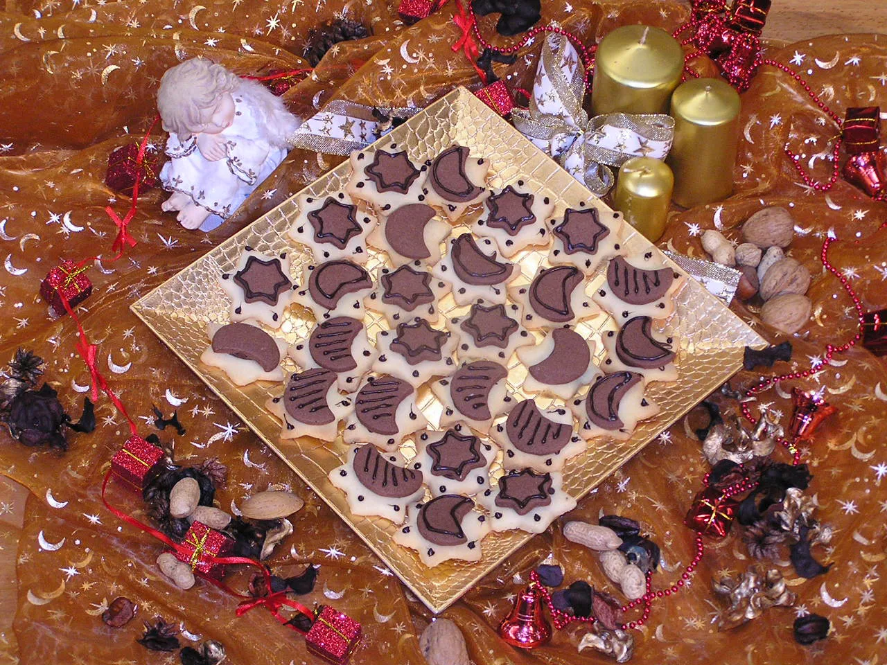 Nougat Mond-Sterne Gebäck mit Schokoladendekor auf goldener Platte mit weihnachtlichen Dekoelementen