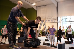 Trainer unterrichtet Gruppe von Personen mit Sandsäcken während Live-Workshop-Session