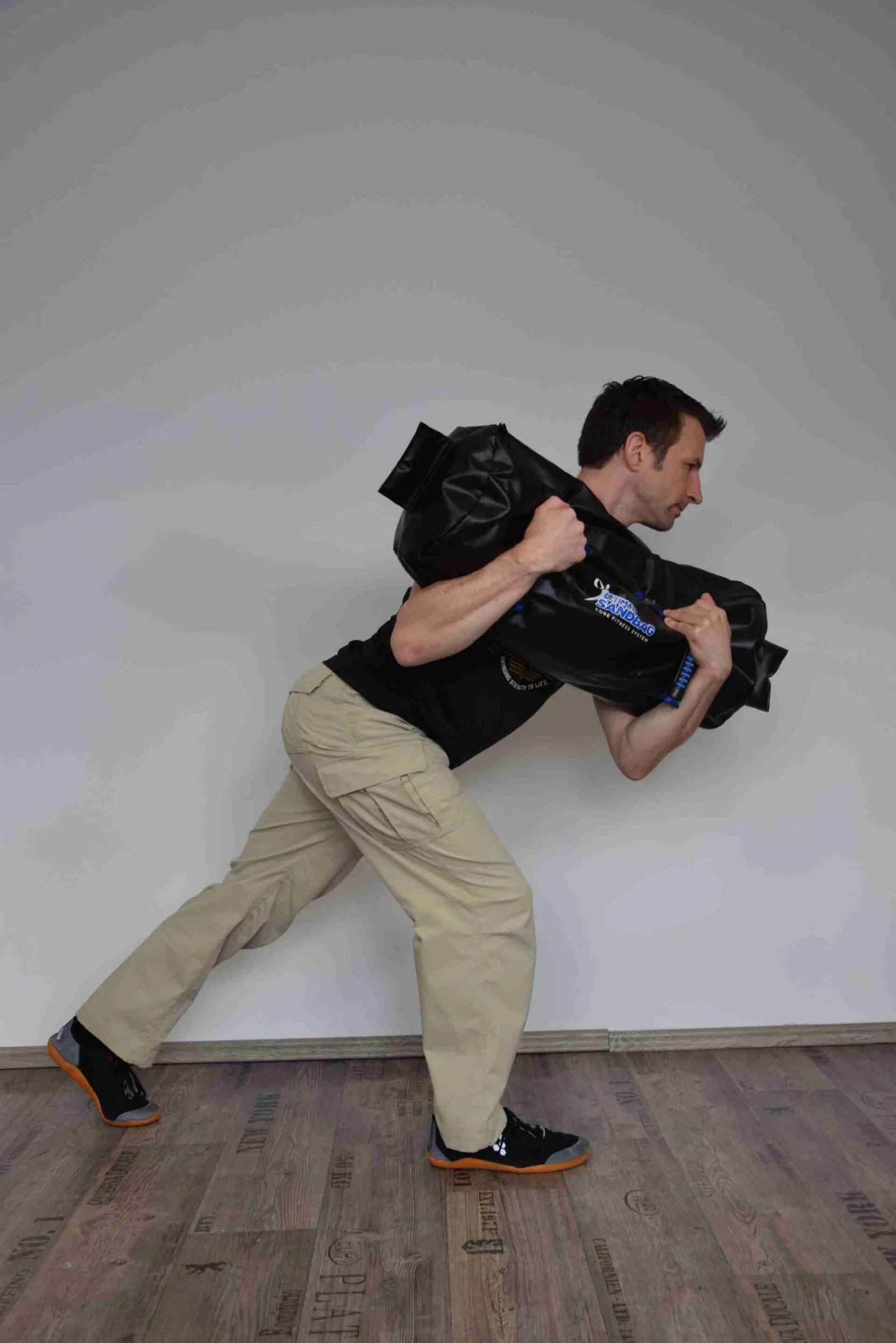 Mann führt Sandsack-Übung in Ausfallschrittposition durch, dynamisches Krafttraining