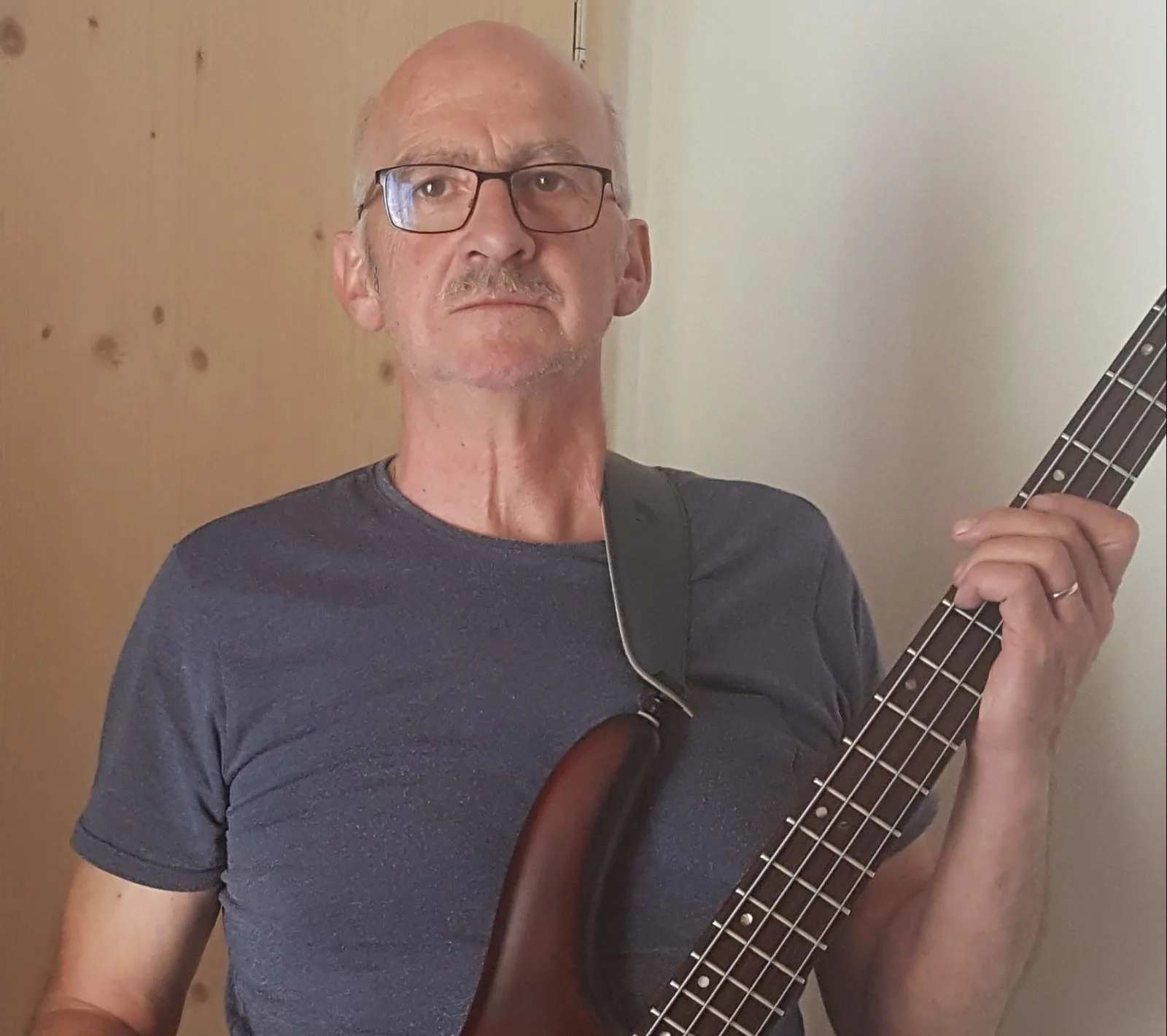 Marco Hartmann aus der Schweiz hält E-Bass mit beigefarbenem Hals, trägt dunkles Shirt