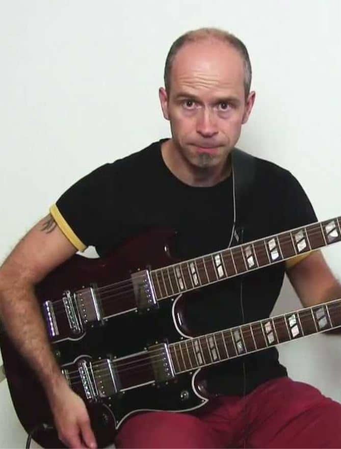 Andreas Vockrodt, E-Gitarrenlehrer, mit Doppel-Halsgitarre und Kopfhörern in schwarzem Shirt