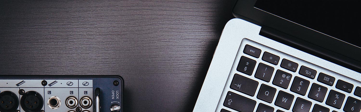 Arbeitsplatz mit Audio-Interface und Laptop-Tastatur auf grauer Oberfläche