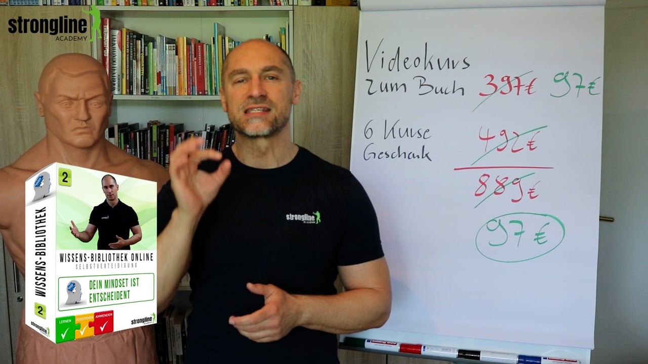 Effektive Selbstverteidigung – Videotraining zum Selbstschutz 4 Marcel Descy vor Bücherregal präsentiert Kurs-Box neben Flipchart mit Preisaufstellung