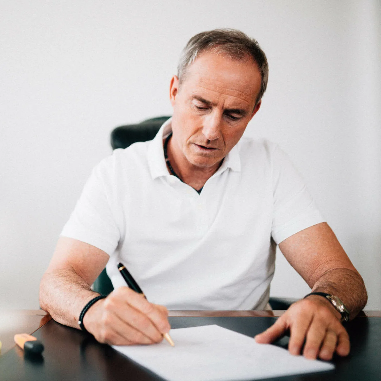 Portrait des Autors Bodo Schäfer in weißem Poloshirt am Schreibtisch